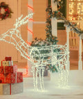 Illuminated wireframe reindeer decoration with Christmas lights and presents on a festive porch.