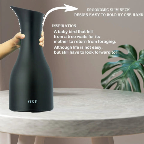 Hand holding a black carafe with ergonomic design, labeled 'OKE', featuring an inspirational quote beside a potted plant.