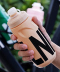 Person holding a Leak Resistant Squeeze Lid Water Bottle For Biking And Hiking in beige with black lettering
