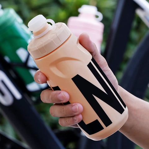 Person holding a Leak Resistant Squeeze Lid Water Bottle For Biking And Hiking in beige with black lettering
