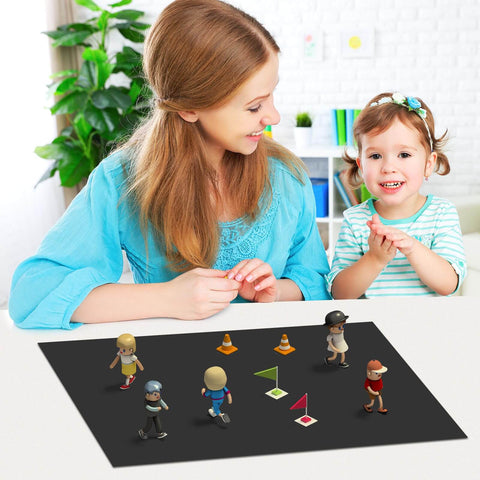 Mother and child playing with small figures on a magnetic receptive sheet on the table in a bright room.