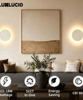 LUXLUCIO Hardwired 9" Round Backlit White Modern Indoor LED Wall Sconce illuminating a cozy living room with artwork.