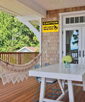 Caution Keep Clear Of Moving Parts 8 By 12 Inch Aluminum Sign for Workshop on porch wall, visible with hammock and table.