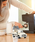 Woman brewing coffee beside Metal Coffee Truck With Burlap Sack Farmhouse Kitchen Decor Mini Pickup on counter
