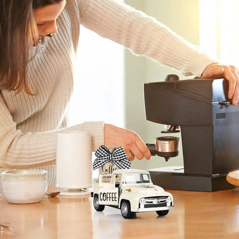 Woman brewing coffee beside Metal Coffee Truck With Burlap Sack Farmhouse Kitchen Decor Mini Pickup on counter
