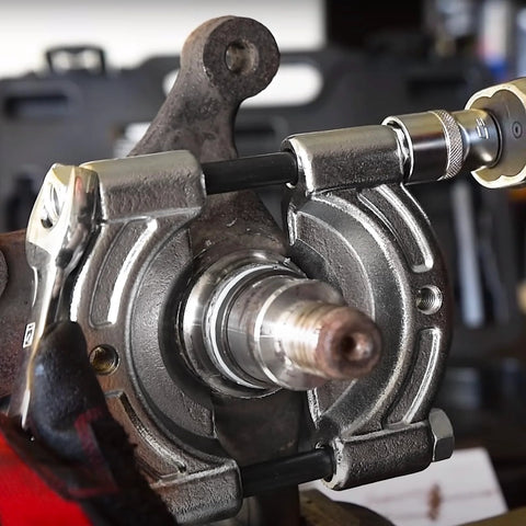 14 Piece Bearing Puller Kit With 5 Ton Capacity shown in use on automotive hub, demonstrating dual jaw sizes and heavy-duty construction.