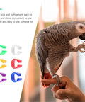 Parrot perched on finger beside colorful clips, 200Pcs Pigeon Leg Rings Set For Easy ID Of Pigeons Parrots And Small Birds Colorful Clips