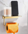 Solid Brass Toilet Paper Holder With Gold Finish, Hotel Style Tissue Roll Holder Plus Built In Cell Phone Shelf, Rust Resistant Chrome Finish, Pro Grade Heavy Duty Bathroom Organizer For Rolls Up To 5.31 Inches, shown holding orange toilet paper.