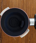 Top-down view of 54mm espresso backflush cleaning disc, black plastic, inside a portafilter