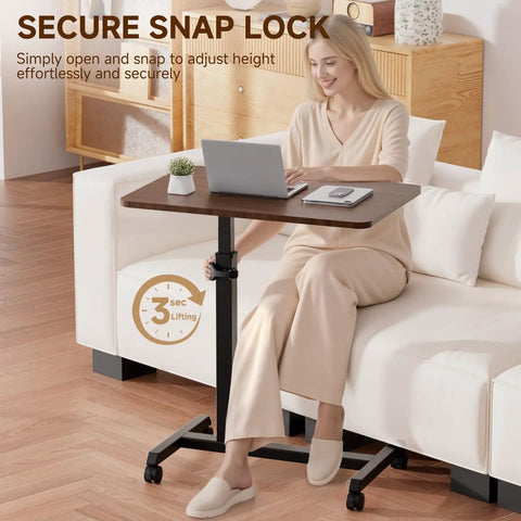 Compact Standing Desk On Wheels With Foldable 24 Inch Desktop Lockable Casters Adjustable Height From 25 To 36.5 Inches Ideal Overbed Or Home Office Laptop Table In Walnut Finish used by woman on sofa