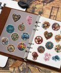Dope Steampunk Gear Sticker Set 50pc for Journaling with vintage clockwork gears, resin elements, on a notebook next to a laptop.