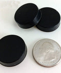 Three black Sorbothane Heavy Duty Vibration Isolation Circular Disc Pads 0.25 Inch Thick 1 Inch Diameter with a quarter for scale