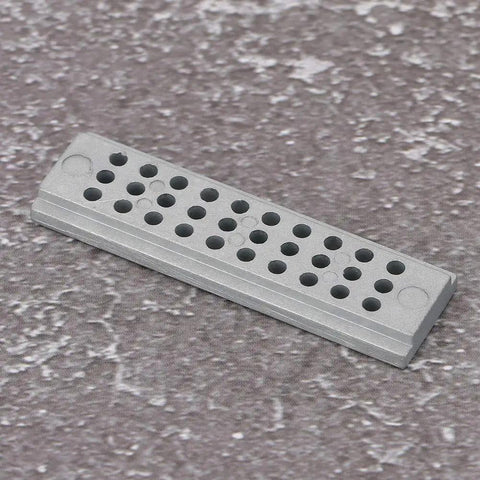 Riveting Stake Block For Watch Repair 30 Holes Steel Punch Block resting on textured surface showing hole details.