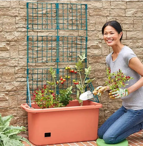 Person tending a Movable 58 Inch Self Watering Veggie Planter With Wheels And Trellis For Easy Sun Tracking, outdoor garden