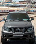 Premium Steel Ditch Light Brackets For 2005-2017 Nissan Xterra And Frontier close-up view on vehicle front highlighting design.