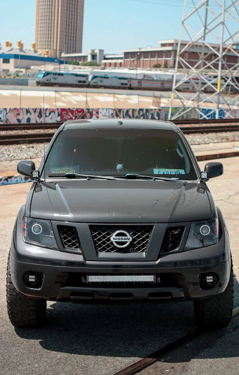 Premium Steel Ditch Light Brackets For 2005-2017 Nissan Xterra And Frontier close-up view on vehicle front highlighting design.