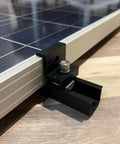 Close-up of black aluminum clamp from Solar Panel Mounting Brackets Roof Kit With Rails And Clamps For 1.18 To 1.38 Inch Panel Thickness A Row Roof Assembly On Tin Or Flat Sheet Rooftops Aluminum Alloy 4 Pack Black securing panel edge.