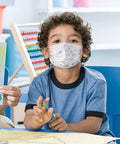 Child wearing kid friendly disposable face masks 50 pack 3 ply breathable protective masks for boys and girls soft ear loops blue.