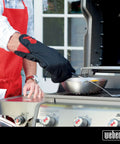 Person using Barbecue Grill Mitt Black Cotton with Red Kettle Embroidery Foldable Cuff to handle hot pan on outdoor grill