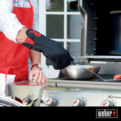 Person using Barbecue Grill Mitt Black Cotton with Red Kettle Embroidery Foldable Cuff to handle hot pan on outdoor grill