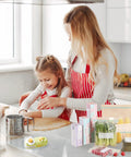 Mother and daughter using No Sweat Mini Bag Sealer and Cutter; kitchen with snacks and sealed food. Portable green device visible.
