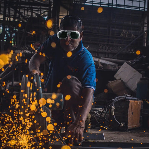 A worker using Badass Welding Glasses With Anti Glare Black And Gray Lenses during metal fabrication, protecting eyes from sparks.