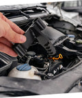 Close-up of black FELTECHELECTR flywheel holding tool held by hand over a car engine bay.
