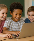 Three children sitting at a table using a laptop in a classroom setting, smiling and engaged.