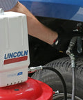 Lincoln 917 Pro Grade 50 To 1 Pneumatic Grease Pump in use, attached to a red base and vehicle tire visible