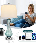 Woman smiling while using phone with Coastal Glass Table Lamp Set Of 2, 27.5 Inch Blue Nautical Bedside Lamps visible, USB ports shown.