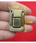Close-up of hand holding one latch from Sturdy Iron Box Hasps Set Of 10 Latches With Antique Bronze Finish And Gold Tone, 25x37mm size.