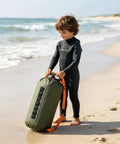 Child holding Do It All 3 In 1 Inflatable Water Weight Bag For Camping, Swim Float And Tent Anchor, 10L Green on beach
