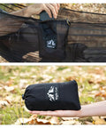 Person holding Ultralight Pocket Hammock For Solo Adventures in pocket, tear-resistant HMPE, ultra compact bag in hand on grass.