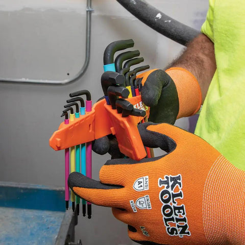 Person holding color coded hex key wrench set with long arm L style and ball end SAE and metric 18 piece kit in workshop.