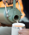 Person pouring from a Half Gallon Stainless Steel Water Jug With Ceramic Lined Interior Double Wall Insulated Cooler Bottle.
