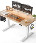 CubiCubi Large Electric Height Adjustable Standing Desk Maple Surface with dual monitors and office accessories displayed.