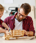 Father and son working on a wooden toy truck using Pro Level Basswood Sheets 24 Pack 4X6X1/16 Inch Unfinished Wood.
