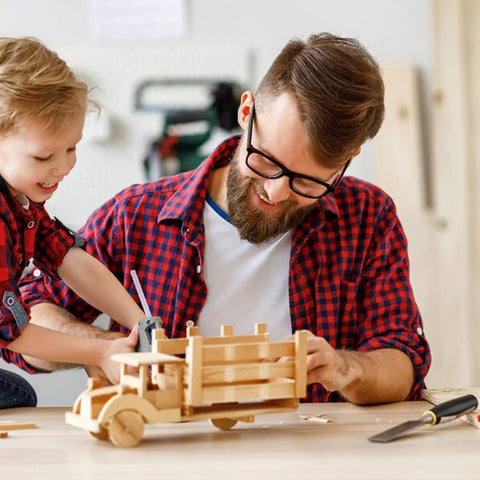Father and son working on a wooden toy truck using Pro Level Basswood Sheets 24 Pack 4X6X1/16 Inch Unfinished Wood.