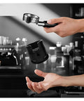 58mm Adjustable Portafilter Holder And Espresso Tamping Station being held above a hand for easy use and stability.