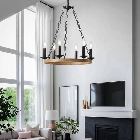 Six Light Farmhouse Chandelier with Rustic Industrial Wagon Wheel Design in Black hanging in a modern living room