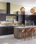 Modern kitchen with island, dark cabinets, stainless steel appliances, and wooden chairs under pendant lighting.