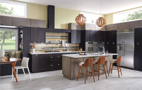 Modern kitchen with island, wooden chairs, and stainless steel appliances, featuring dark cabinets and natural light.