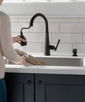 Woman using Emmeline Matte Black Metal Soap Dispenser 13 Oz Bottle, Refillable From Above The Deck, Fits One Three Eighths Inch Hole
