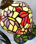 Lily Flower Tiffany Style Stained Glass Table Lamp With Girl Figurine Base close-up, showing colorful stained glass design and warm glow.