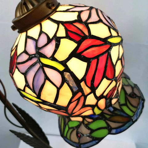 Lily Flower Tiffany Style Stained Glass Table Lamp With Girl Figurine Base close-up, showing colorful stained glass design and warm glow.