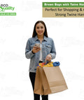 Smiling woman holding Large Brown Paper Bags With Handles 14x8x16 Inches Bulk Takeout Grocery Gift Bags, filled with items.