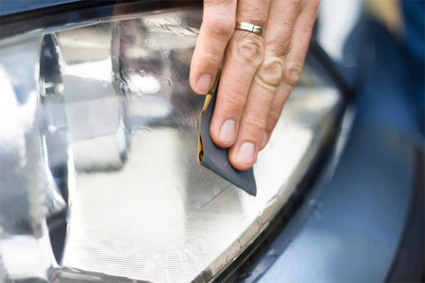 Person using 90 Piece Sandpaper Assortment Set with Wet Dry Grit Range from 400 to 7000 for automotive car painting on headlight