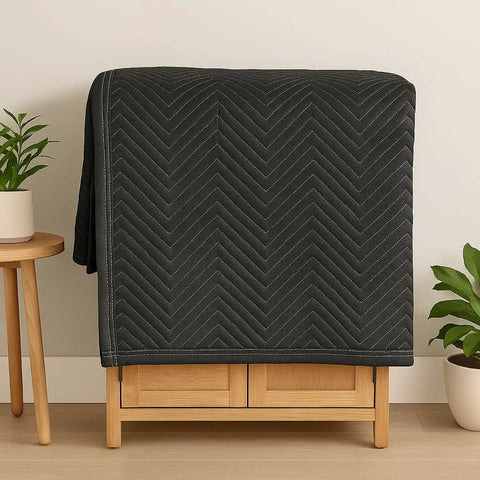Essentials Moving Blanket 40x72 Pro Quilted Furniture Pad for Movers and Packers, folded on storage cabinet, black fabric