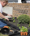 Man using 246 Ft No Dig Garden Edging Kit with 4 Inch Tall Landscape Border Rolls in yard, includes rolls and spikes