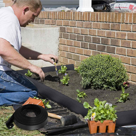 Man using 246 Ft No Dig Garden Edging Kit with 4 Inch Tall Landscape Border Rolls in yard, includes rolls and spikes
